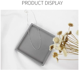 Minimalist S925 sterling silver barrel pendant necklace shown on a gray cement display tray