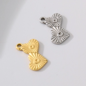 Détail de pendentifs en double cœur or et argent avec une texture de rayons de soleil
