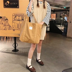 Detail of a large mustard yellow canvas tote bag worn on shoulder in street style