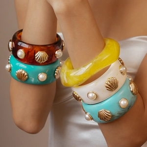 Vintage resin cuff bangles with pearl and shell accents in various colors on a model