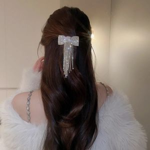 Détail d'une pince à cheveux avec nœud argenté et pampilles en strass étincelants
