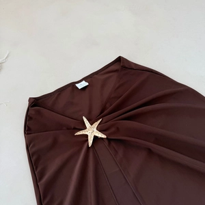 Détail de la jupe en mesh marron avec boucle étoile de mer dorée et texture plissée