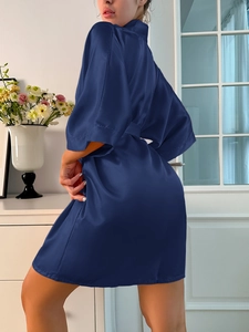 Détail d'un peignoir en satin bleu foncé montrant la texture soie et la ceinture