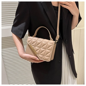 Elegant beige quilted crossbody bag with gold chain strap shown on a model in a black blazer