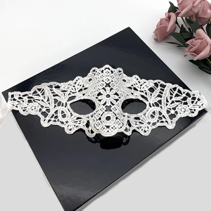 Elegant white lace masquerade mask with silk ribbons on a luxury black display box
