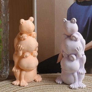 Detail of stacked frog animal statues in matte orange and purple resin for home decor