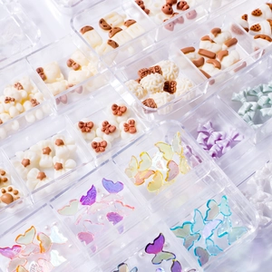 Assorted 3D nail art charms in a clear grid box featuring resin bears and bows