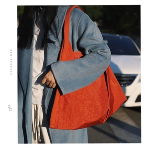 Detail of trendy orange oversized tote bag featuring a textured pleated design and soft fabric