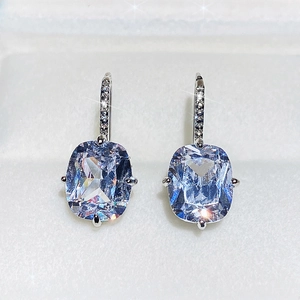 Detail of light blue cushion-cut gemstone earrings in a velvet jewelry box