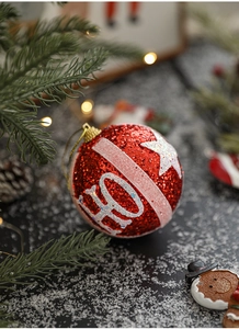 Close-up of a red Christmas ornament with white glitter HO pattern on a festive tree
