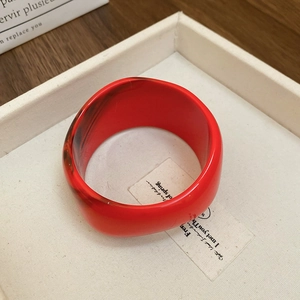 Detailed macro view of vintage red marble resin wide bracelet on a minimalist tray
