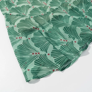 Close-up of light green dress fabric featuring dark green fan patterns and red dots