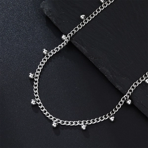 Detailed close-up of a silver stainless steel chain with small bead accents on black stone