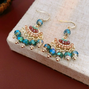 Detail of vintage earrings with green crystals and red-brown beads on gold base