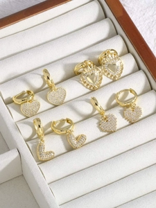 Macro shot of gold-plated heart and letter L earrings set with sparkling cubic zirconia