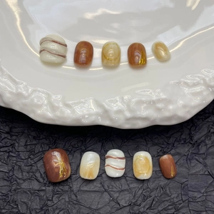 Handmade brown latte ombre press-on nails with amber tones, gold foil, and embossed lines
