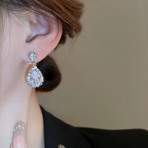 Close-up of sparkling waterdrop zircon stud earring worn by a model in silver finish