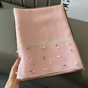 Detail of pink silk scarf with elegant bead accents and shimmering metallic stripes