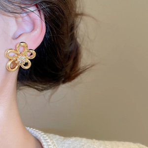 Close-up of golden flower stud earrings with hollow petals and zircon inlay for women