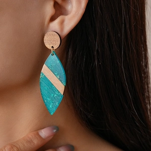 Detail of bohemian wood and teal acrylic leaf earring on a model with close-up side view