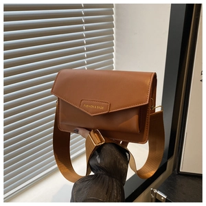 Close-up of caramel leather flap bag with V-cut design and gold metal logo plaque