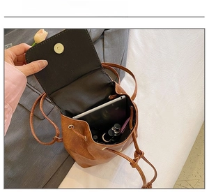 Top view of brown drawstring bucket bag showing interior capacity with tablet and makeup