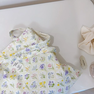 Detail of floral canvas tote bag featuring a woven label and colorful flower pattern