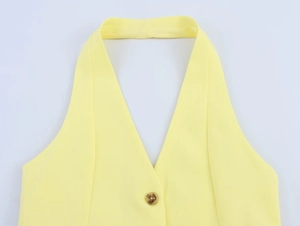 Dettaglio del gilet giallo brillante con scollo all'americana, bottone ambra e scollo a V