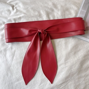 Vue détaillée de dessus d'une ceinture corset large en similicuir rouge avec un nœud