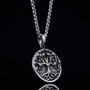Gros plan du pendentif Arbre de Vie en argent avec relief sur un reflet de miroir