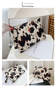 Detail view of cow print envelope clutch bag with zipper and matching wrist strap