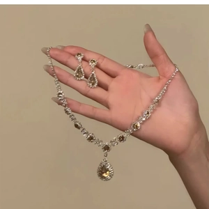 Detailed shot of jewelry set featuring flower crystal necklace and earrings held by hand