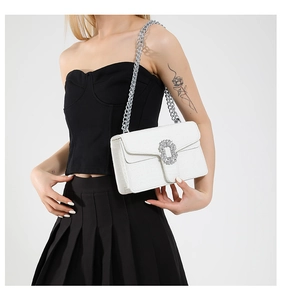 Detail of white crocodile texture handbag with silver chain and rhinestone buckle