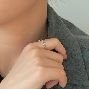 Detailed view of silver smile engraved ring worn by model over a grey blazer