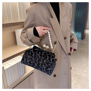 Detail of black leopard velvet shell bag featuring pearl clasp and gold chain strap