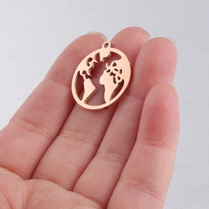 Close-up of a rose gold hollow world map pendant held by hand for size reference