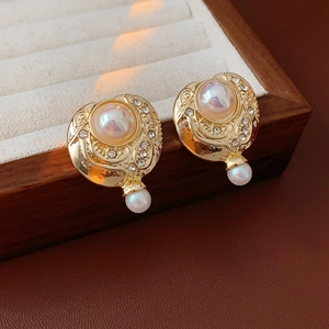Boucles d'oreilles vintage dorées avec perle et strass dans un coffret à bijoux en bois