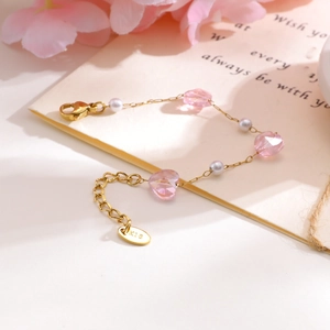 Gold plated children's bracelet featuring pink heart crystals and white pearls