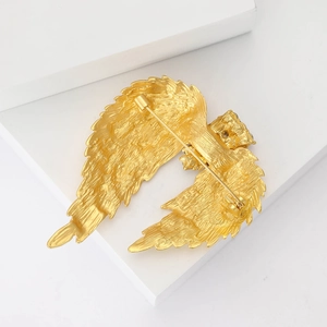 Detailed back view of a golden metal wing brooch showing the safety pin clasp mechanism