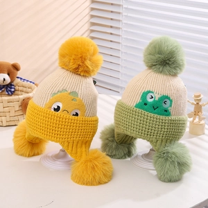 Detailed close-up of knitted baby earflap hats with pom-poms in yellow and green