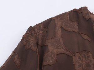 Détail du tissu en maille marron foncé avec une élégante texture florale floquée raffinée