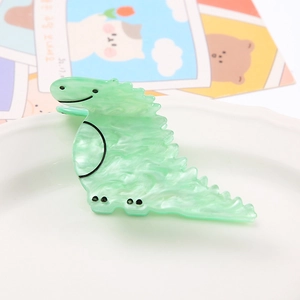 Close-up of a light green marble dinosaur claw clip on a decorative white ceramic plate
