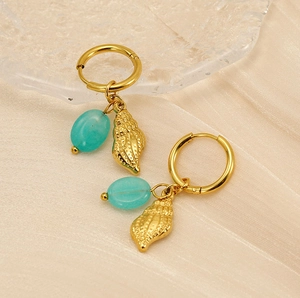 Detailed view of conch shell earrings with blue stones on warm satin background