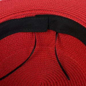 Macro shot of red straw hat interior showing the black sweatband and adjustable drawstring
