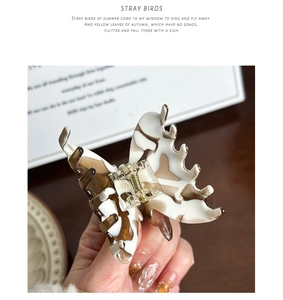 Close-up of vintage creamy coffee acetate butterfly hair claw clip with golden logo detail