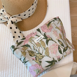 Close-up of floral embroidery on a minimalist jacquard makeup bag with woven brand tag