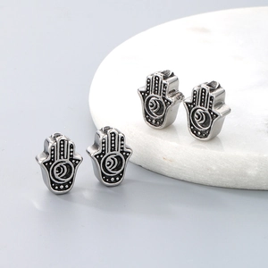 Detailed macro view of four silver stainless steel Hamsa Hand beads for DIY jewelry making