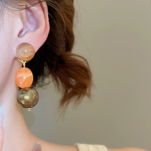 Close-up of geometric marble acrylic ball drop earrings in vintage autumn colors