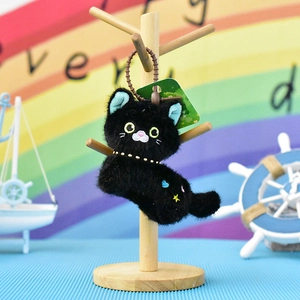 Close-up of a cute black plush cat keychain with embroidered heart and star details