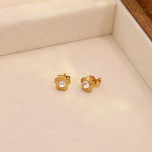 Makroaufnahme goldener Blumenohrstecker mit Zirkonia auf beigem Samt-Schmuckkästchen